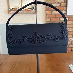 Black evening bag that can be used as a clutch, hand bag, or shoulder bag.